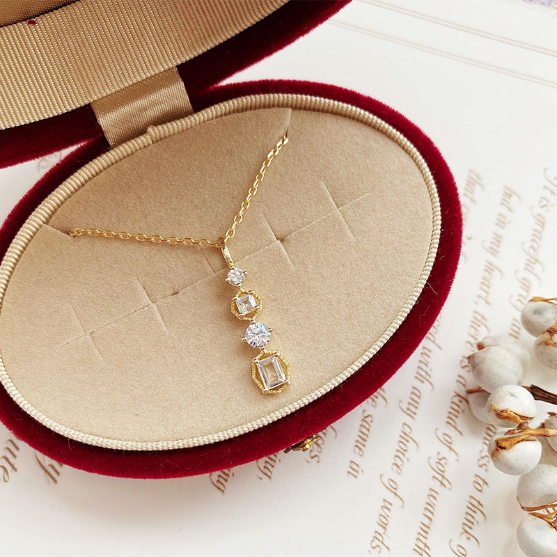 Gold necklace in a red jewelry box with geometric pendant stones, ideal for gifts and special occasions.