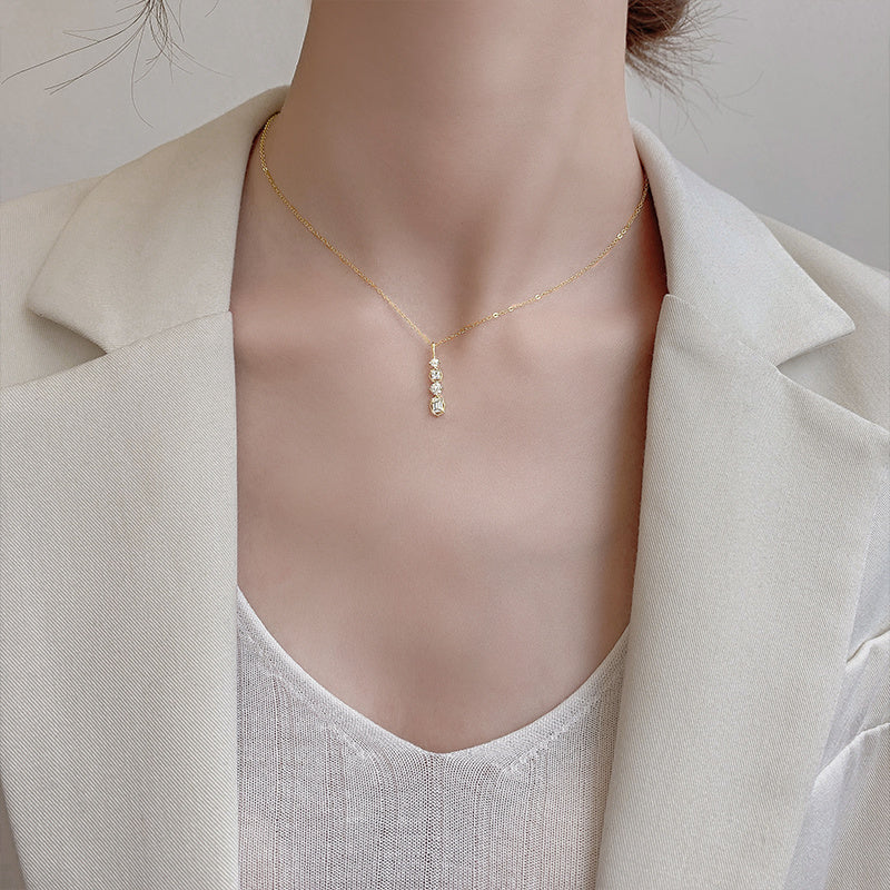 Necklace woman collarbone chain featuring a geometric pendant, styled elegantly with a blazer.