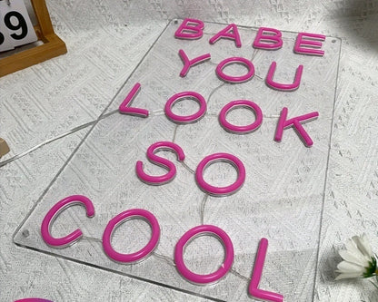 Neon LED light sign with pink letters saying 'Babe You Look So Cool' for vibrant illumination in any space.