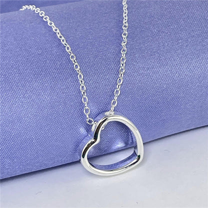 Heart Necklace for Women - Silver chain with heart pendant on purple background.