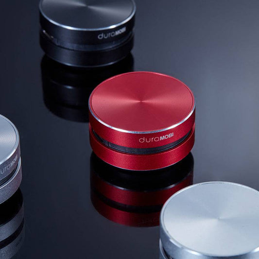 wireless bluetooth compact mini conduction speaker in red black and silver colors on reflective surface